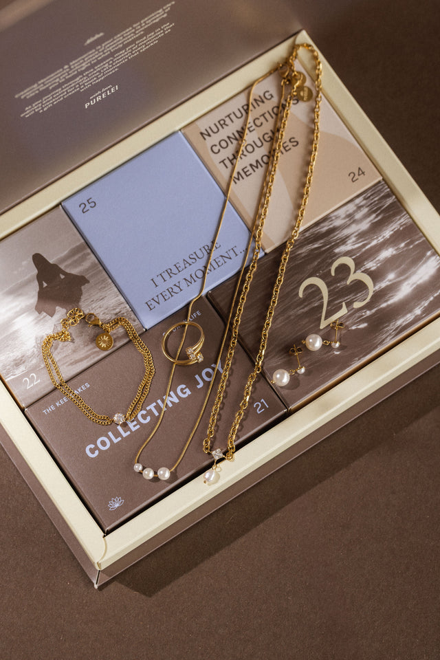 Elegante PURELEI Schmuckstücke in Gold und Perlen auf stilvollem Hintergrund.