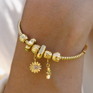 Goldenes Armband mit Blumenanhänger, getragen am Handgelenk, von PURELEI.