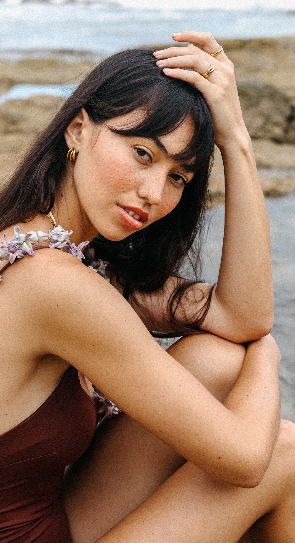 Goldene Creolen und Ringe von PURELEI, elegant und feminin, am Strand getragen.