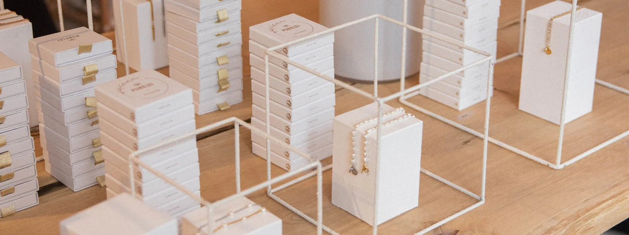 Elegante PURELEI Schmuckpräsentation in weißen Boxen auf hellem Holz, minimalistisch und stilvoll.
