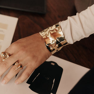 Glänzendes, roségoldenes Armband mit gewelltem Design, getragen auf einem Handgelenk. PURELEI