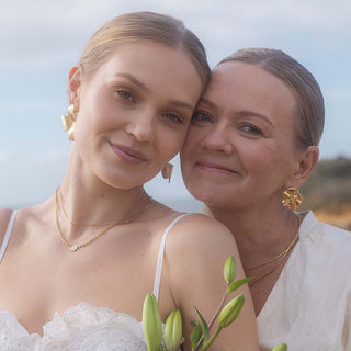 Zarte, roségoldene Ohrringe und Ketten von PURELEI, getragen von Mutter und Tochter am Strand.
