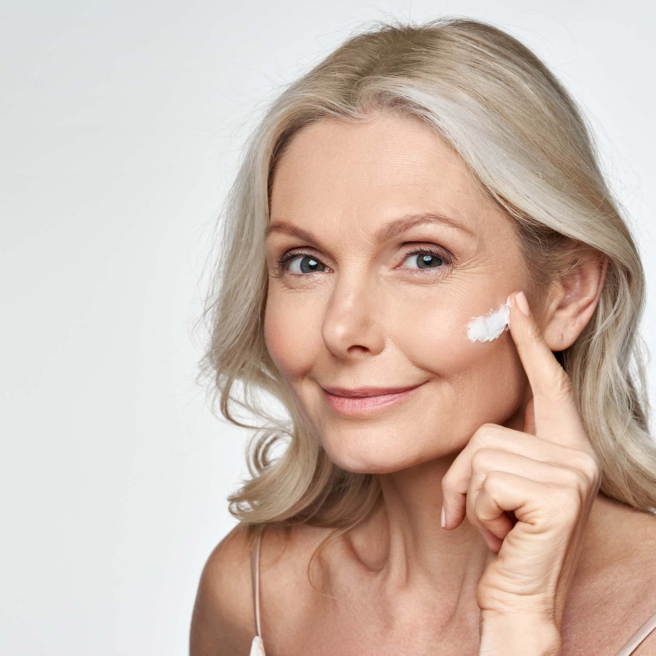 Frau trägt PURELEI Ceramide Barrier Repair Cream auf hellem Hintergrund, strahlt natürliche, gepflegte Haut aus.