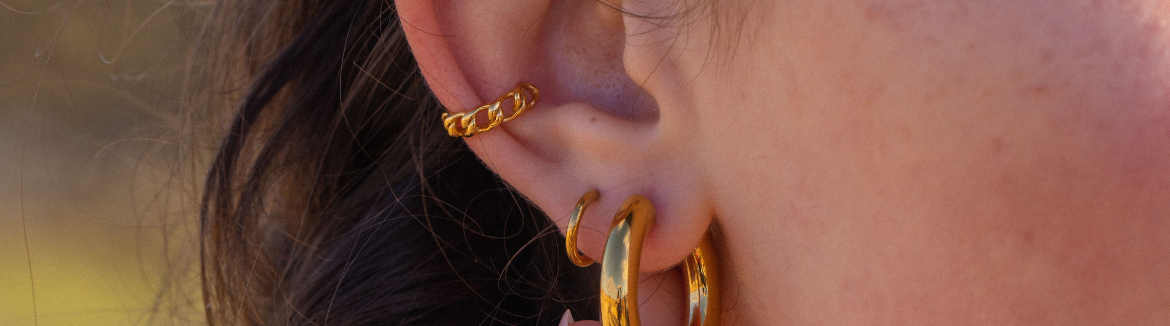 Goldene Creolen und feiner Ring von PURELEI, elegant und feminin, getragen am Ohr.