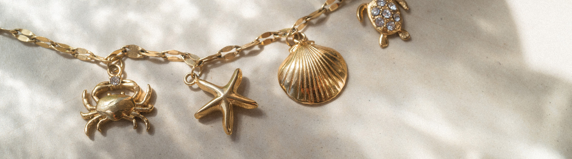 Goldenes Armband mit maritimen Anhängern von PURELEI, elegant und verspielt.