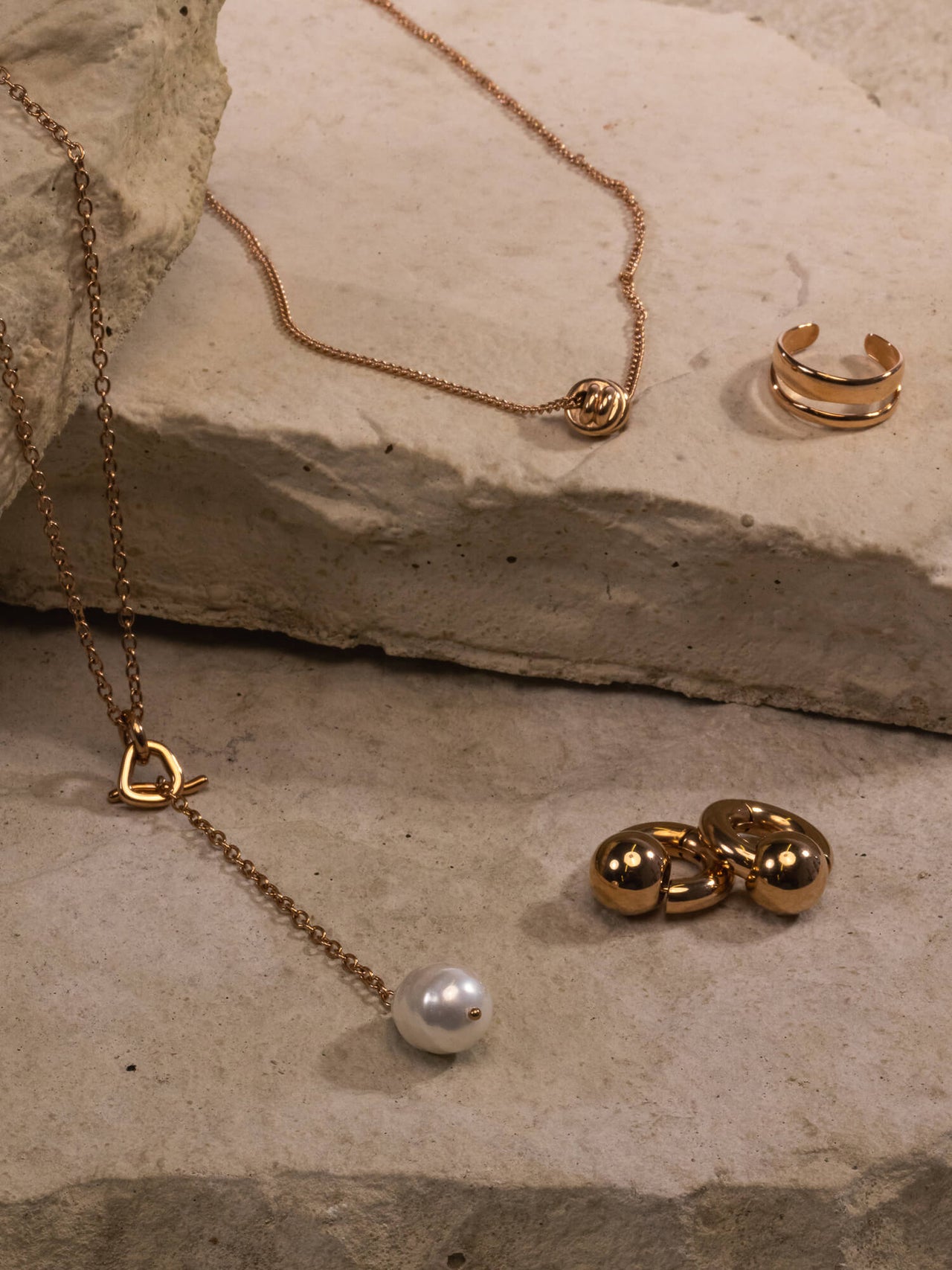 Aloha Schmuckset von PURELEI mit roségoldener Knot-Kette, Perlenanhänger und verstellbarem Ring auf Steinplatte.