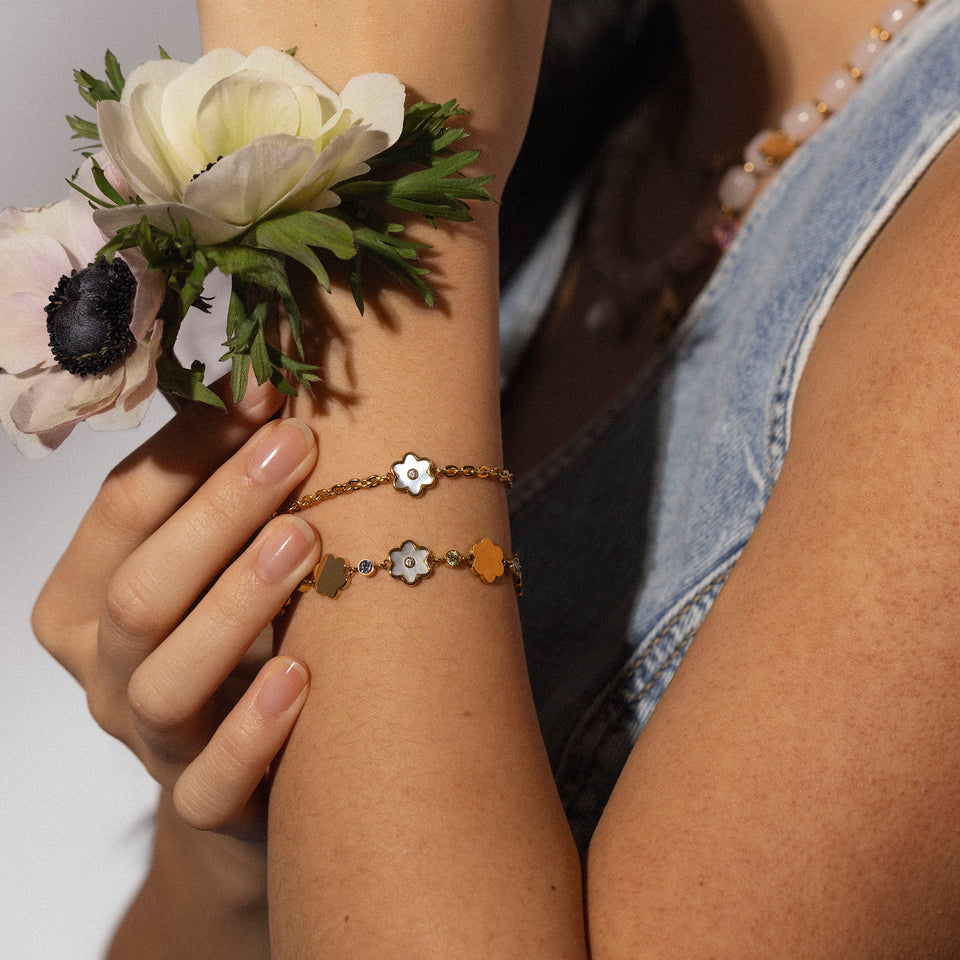 PURELEI Flourish Armband aus 18K Gold mit Muschel-Blütenanhänger und zartem Design am Handgelenk getragen.