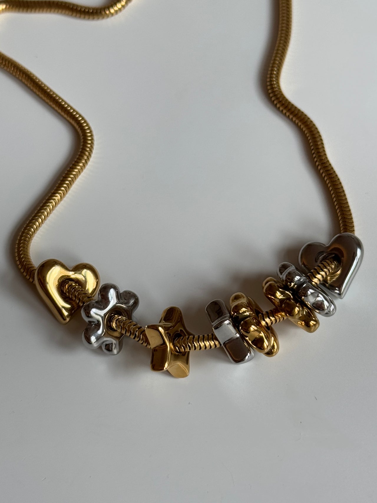 Flower Lucky Charm von PURELEI, gold- und silberfarbene Edelstahl-Charms auf eleganter Kette, warmes Insel-Flair.