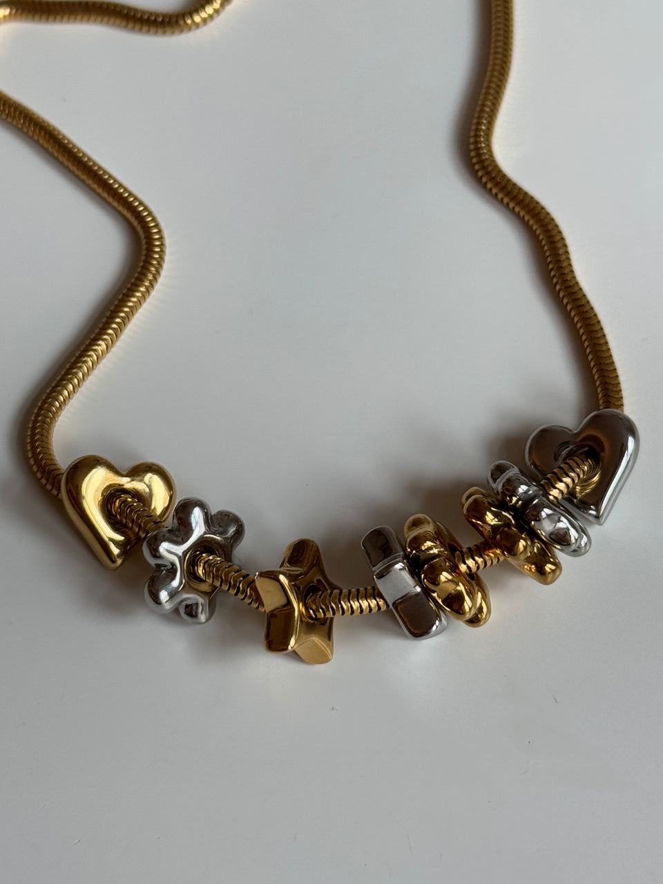 Flower Lucky Charm von PURELEI, gold- und silberfarbene Edelstahl-Charms auf eleganter Kette, warmes Insel-Flair.