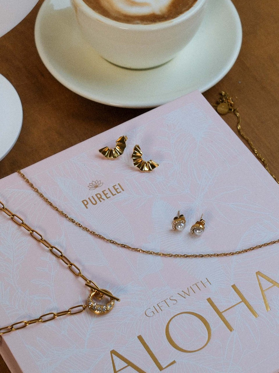 Goldenes PURELEI Air Schmuckset mit Fan-Ohrringen und perlenverzierten Halo-Ohrringen auf Geschenkverpackung
