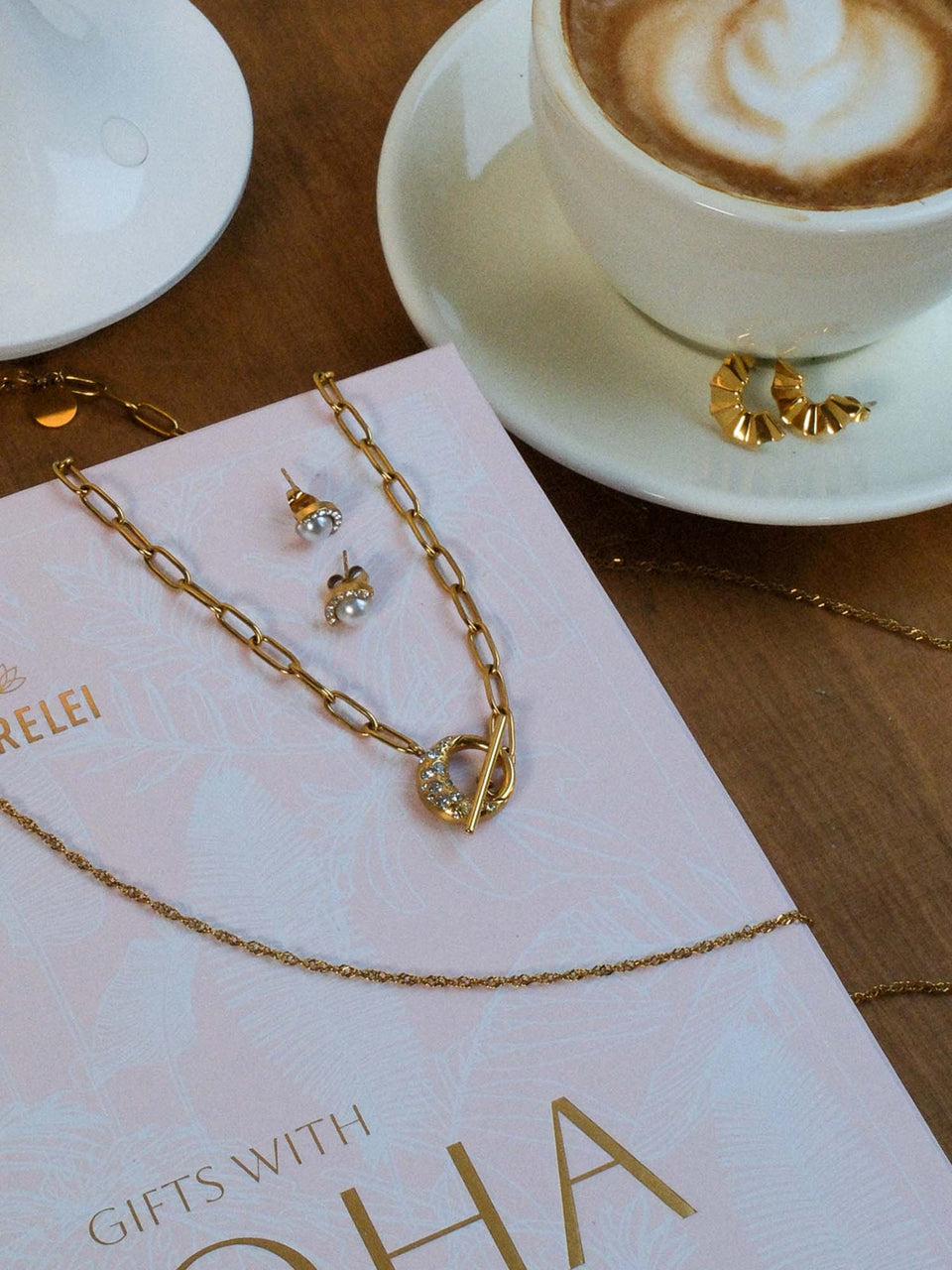 Air Schmuckset von PURELEI mit vergoldeter Kette, Perlenohrringen und funkelndem Mond-Design, elegant arrangiert.