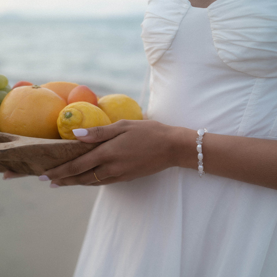 Crystal Wave Armband von PURELEI mit schimmernden Keshi-Perlen und Bergkristall, getragen am Strand in sanftem Licht.