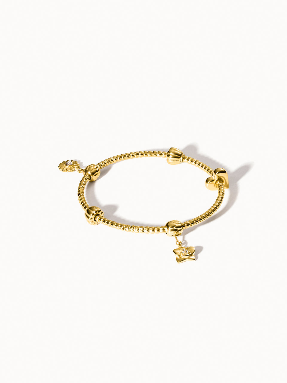 Lei Charm Armreif von PURELEI aus 14K vergoldetem Edelstahl mit Pikakeblüten-Design und zwei Stopper-Charms auf weißem Hintergrund