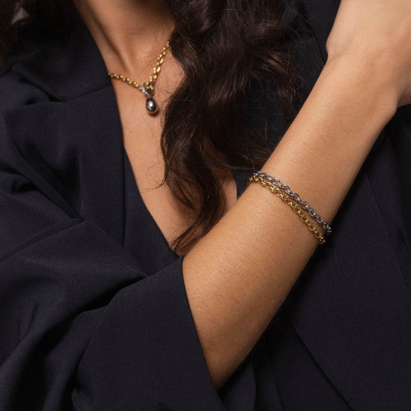 Roségoldenes Armband mit feinen Kettengliedern, getragen mit eleganter Bluse von PURELEI.