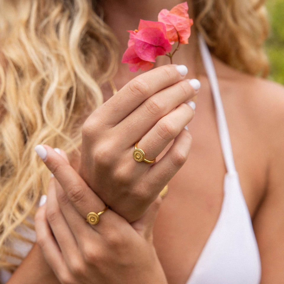 Waina Ring von PURELEI in Gold, mit filigran geprägtem Coin, elegant am Hand getragen im warmen Tageslicht