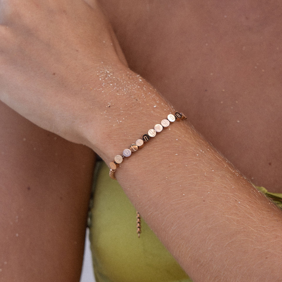 Feel Good Armband von PURELEI, vergoldet, fein mit positiven Botschaften, getragen am sonnenverwöhnten Handgelenk.