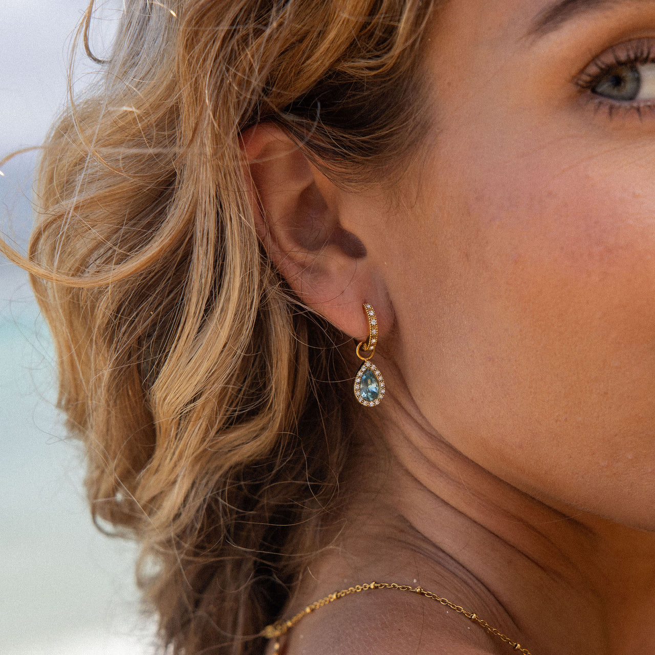 PURELEI Bellezza Ohrringe Gold-Creolen mit aquamarinblauem Tropfenanhänger am Ohr, elegant und feminin.