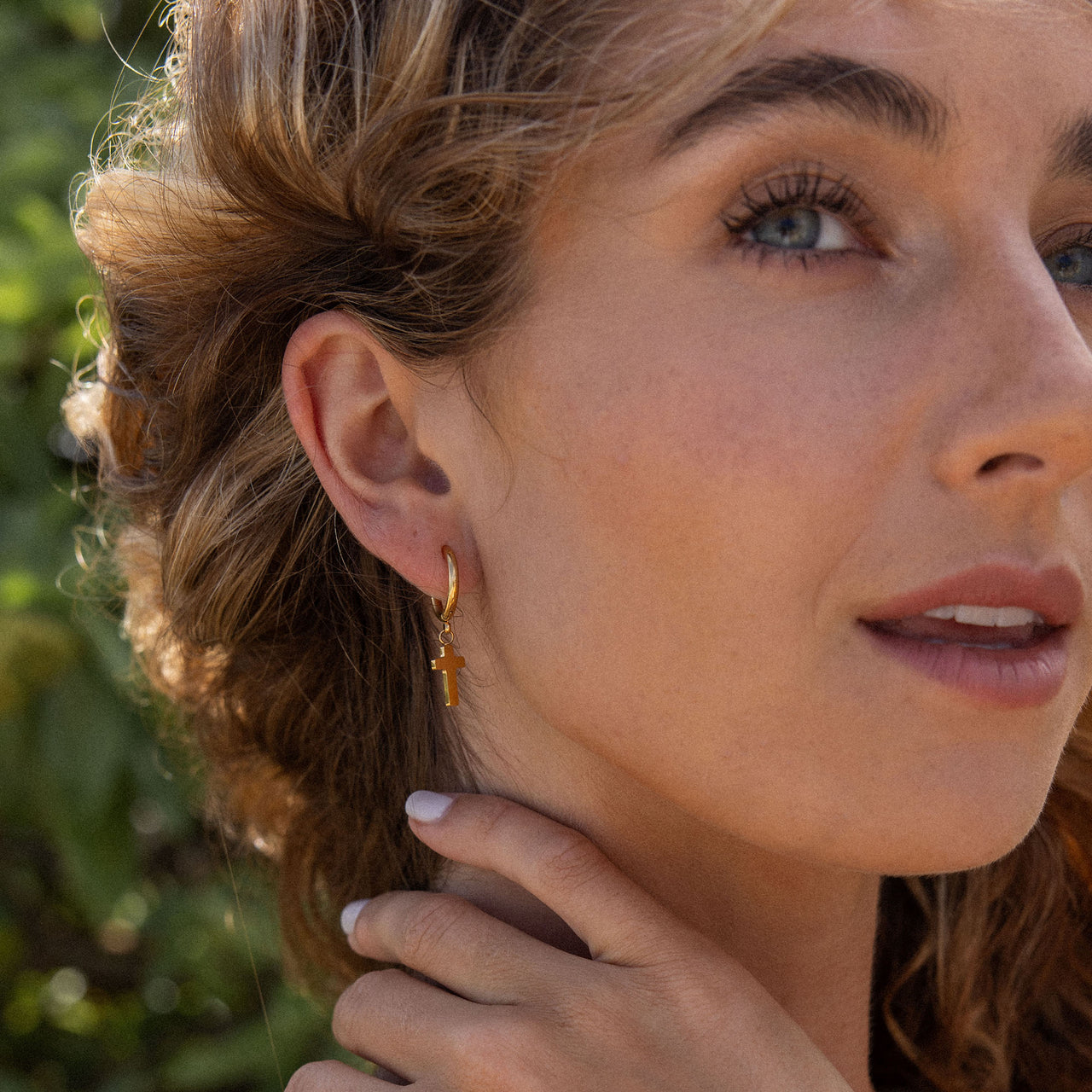PURELEI Cross Creole Ohrringe aus 18K Gold mit Kreuzanhänger, elegant und femininer Island-Spirit, getragen im Sonnenlicht.