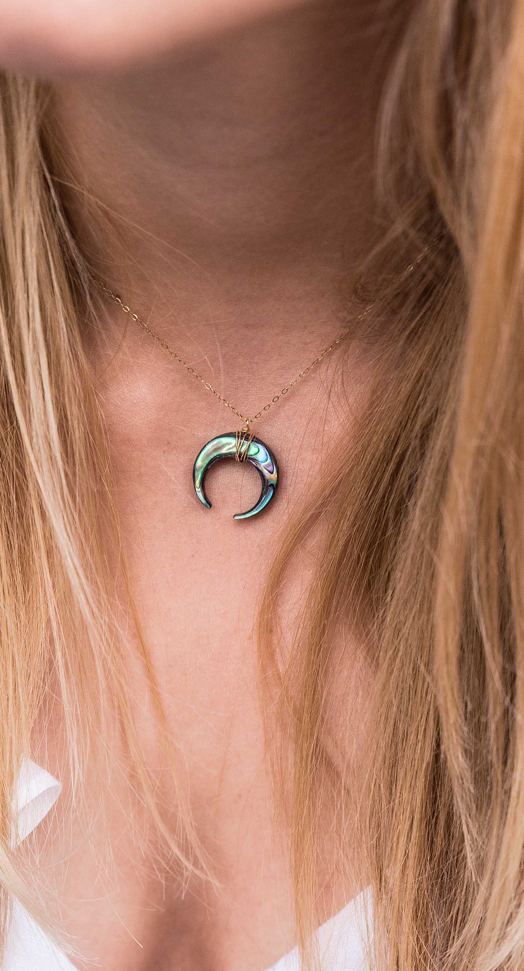 PURELEI Paua Kette mit schimmerndem Abalone-Mondanhänger an zarter vergoldeter Kette, getragen am Dekolleté