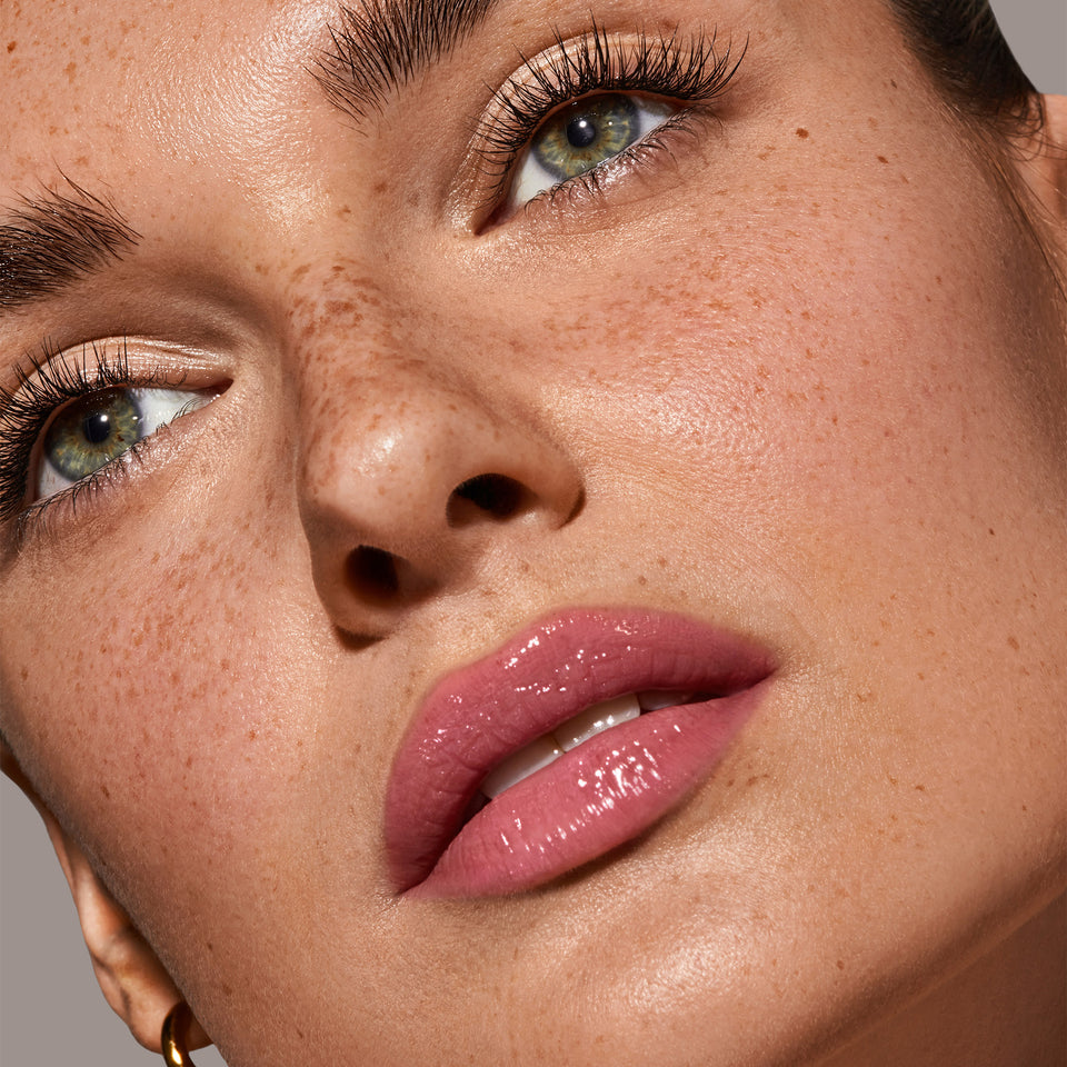 Nahaufnahme eines femininen Gesichts mit glänzender, roséfarbener SPF50+ Triple Lip Care Set Lippenpflege von PURELEI