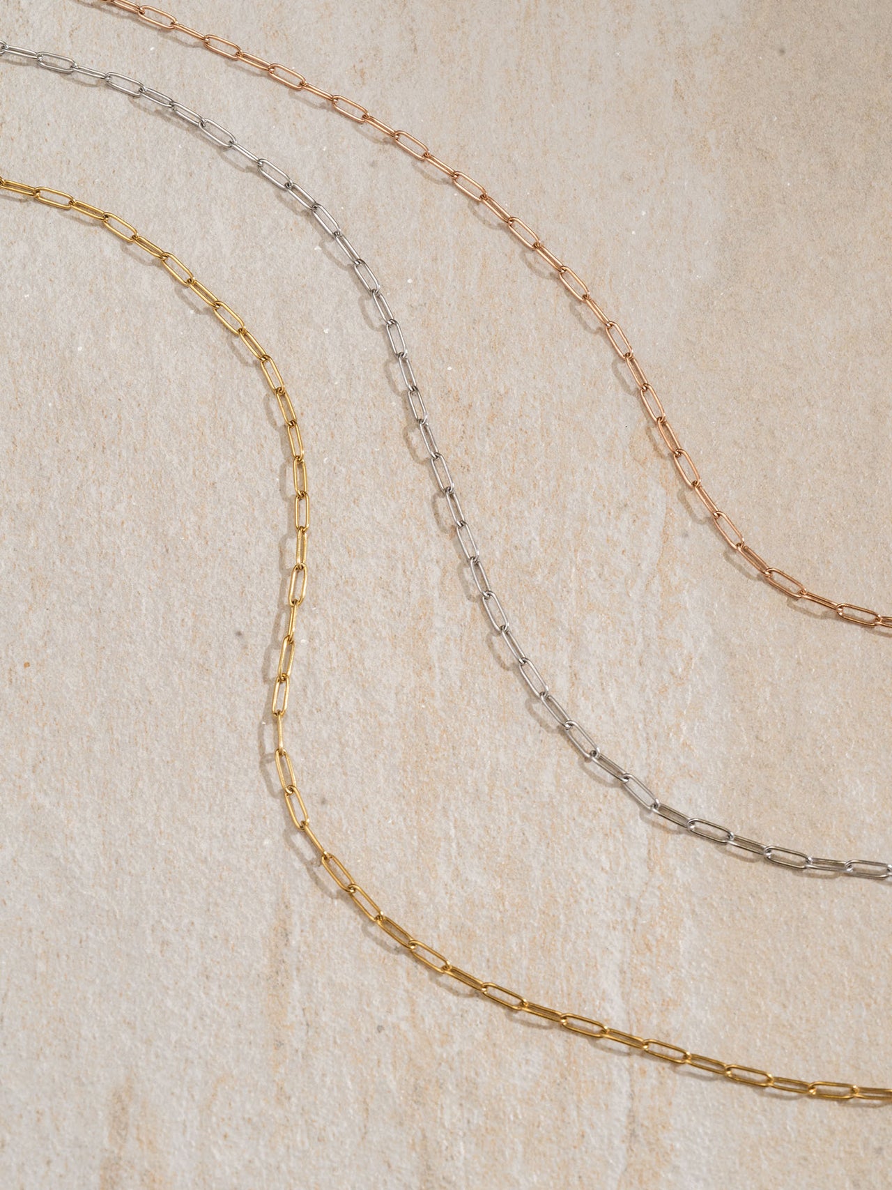 Flex Charm Kette in Gold, Silber und Roségold, filigrane Gliederkette auf hellem Naturstein – PURELEI Eleganz.