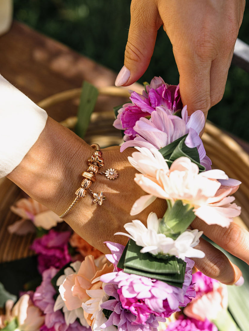 PURELEI Lei Sonnenblumen Charm in Roségold mit Perle und Zirkonia, elegant und feminin am Handgelenk getragen.