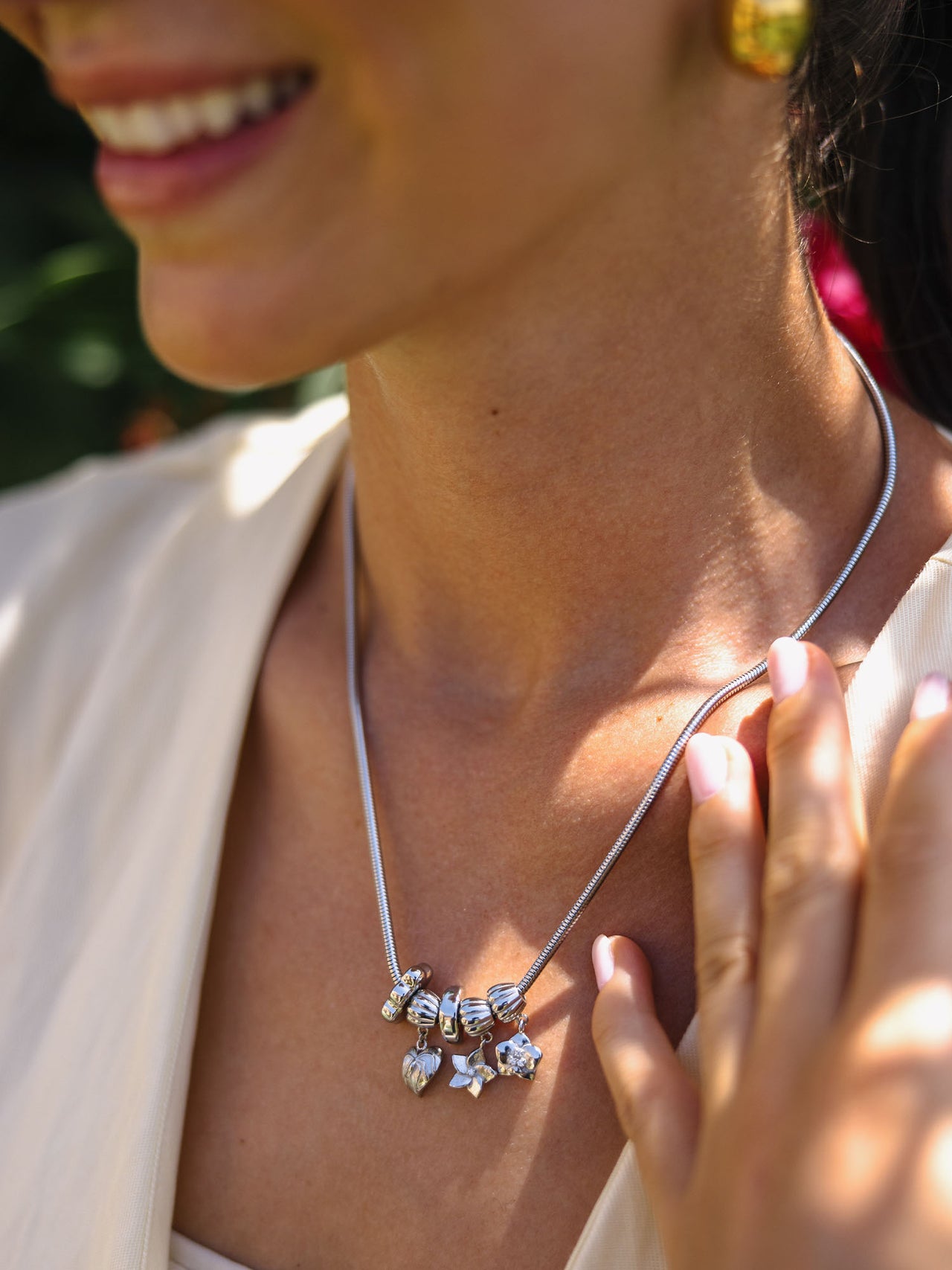 Lei Plumeria Charm von PURELEI in silber mit floralem Anhänger und funkelndem Zirkonia, elegant und feminin getragen.