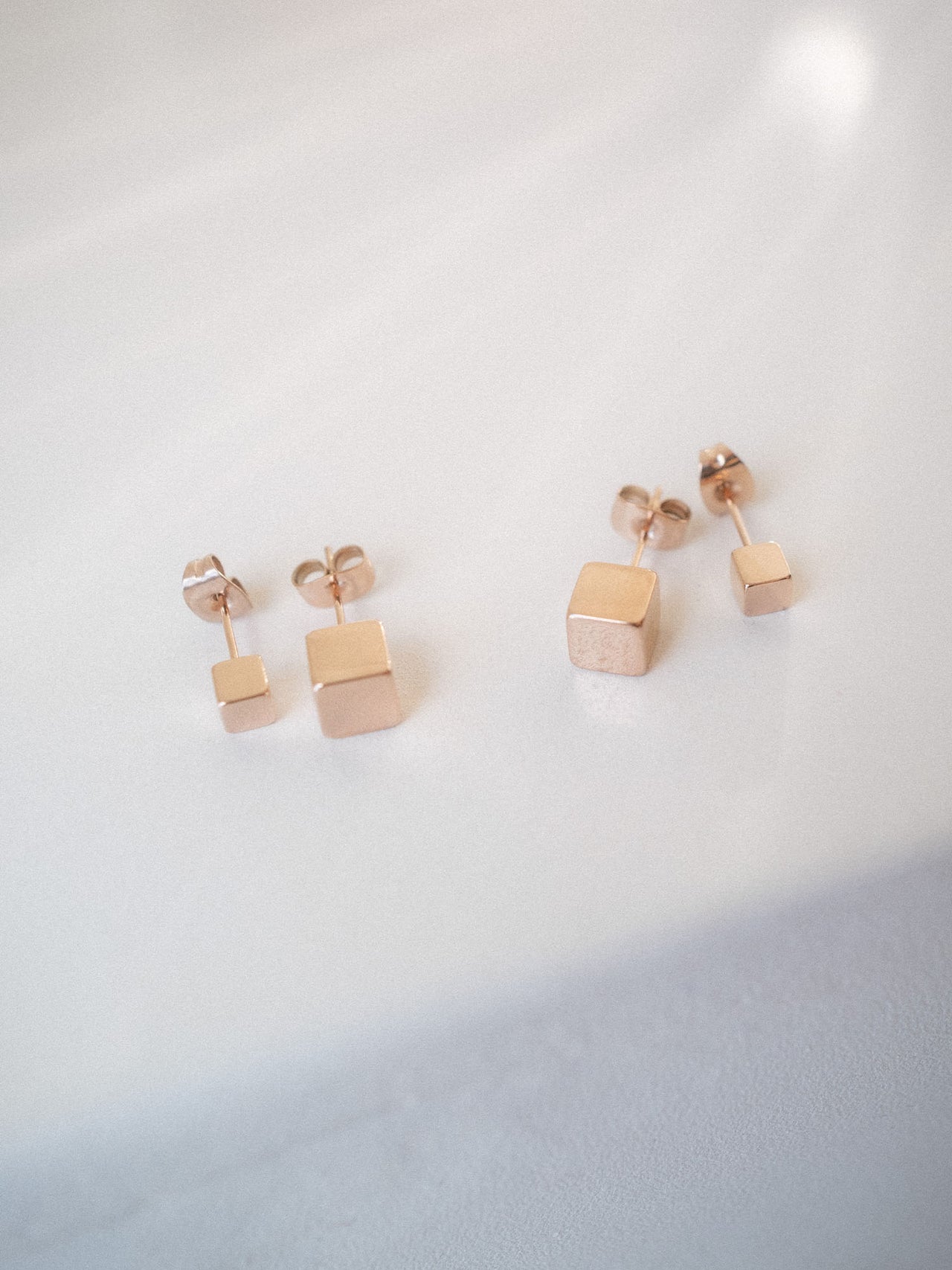 PURELEI Dice Ohrringe Set aus rosévergoldetem Edelstahl mit minimalistischem Würfel-Design in sanftem Lichtschein