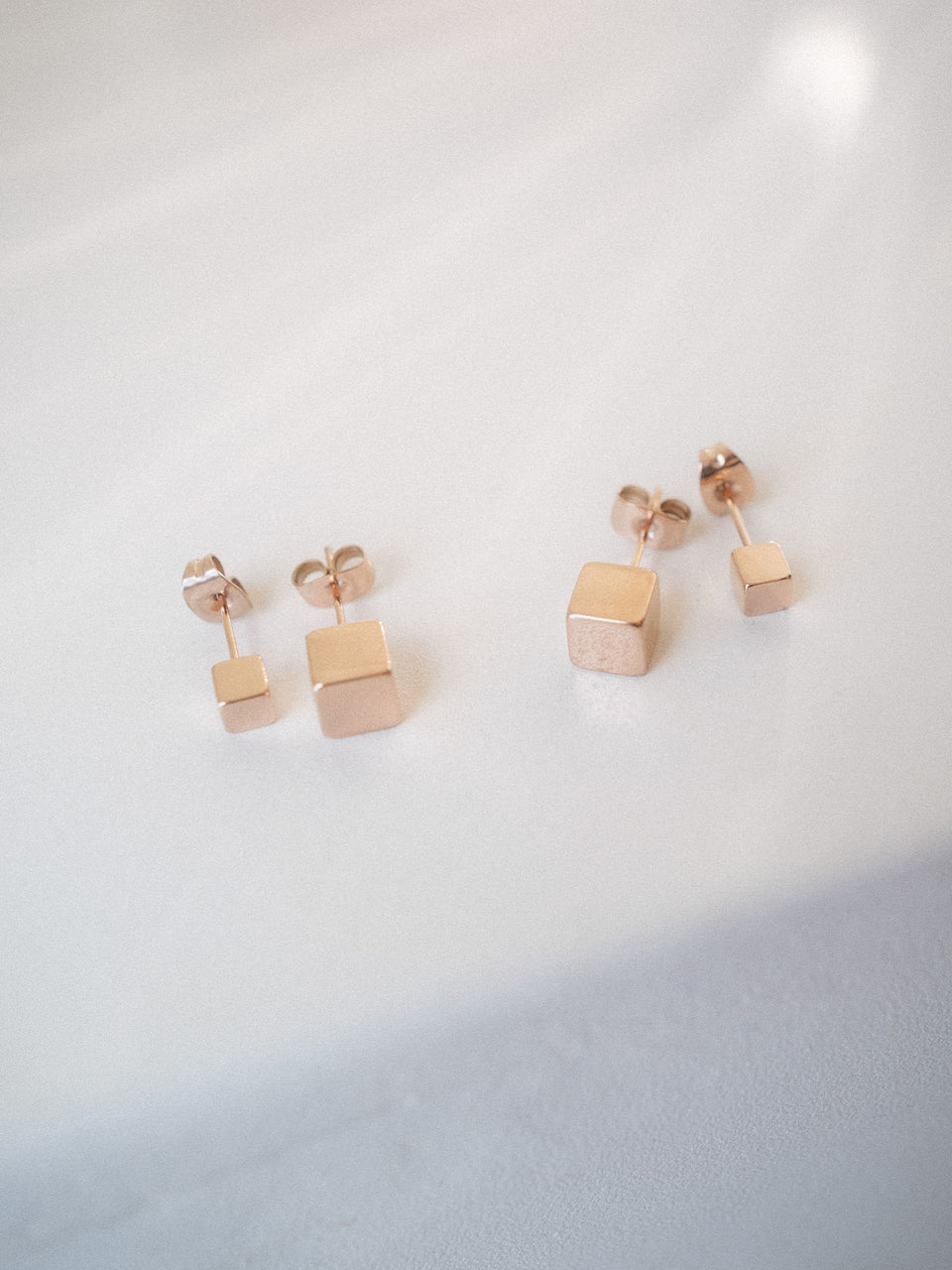 PURELEI Dice Ohrringe Set aus rosévergoldetem Edelstahl mit minimalistischem Würfel-Design in sanftem Lichtschein