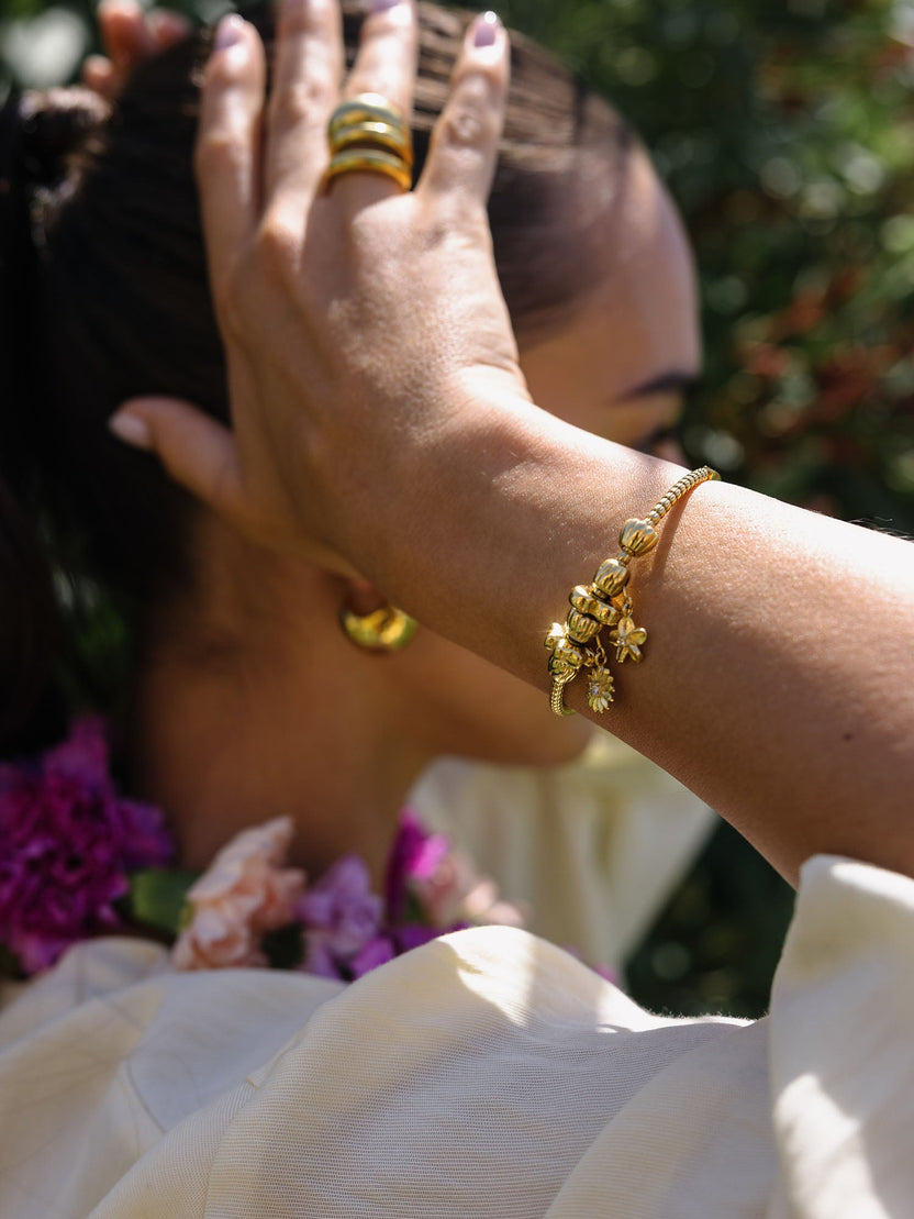 PURELEI Lei Sonnenblumen Charm aus goldfarbenem Edelstahl mit Perle und Zirkonia, elegant und feminin getragen.