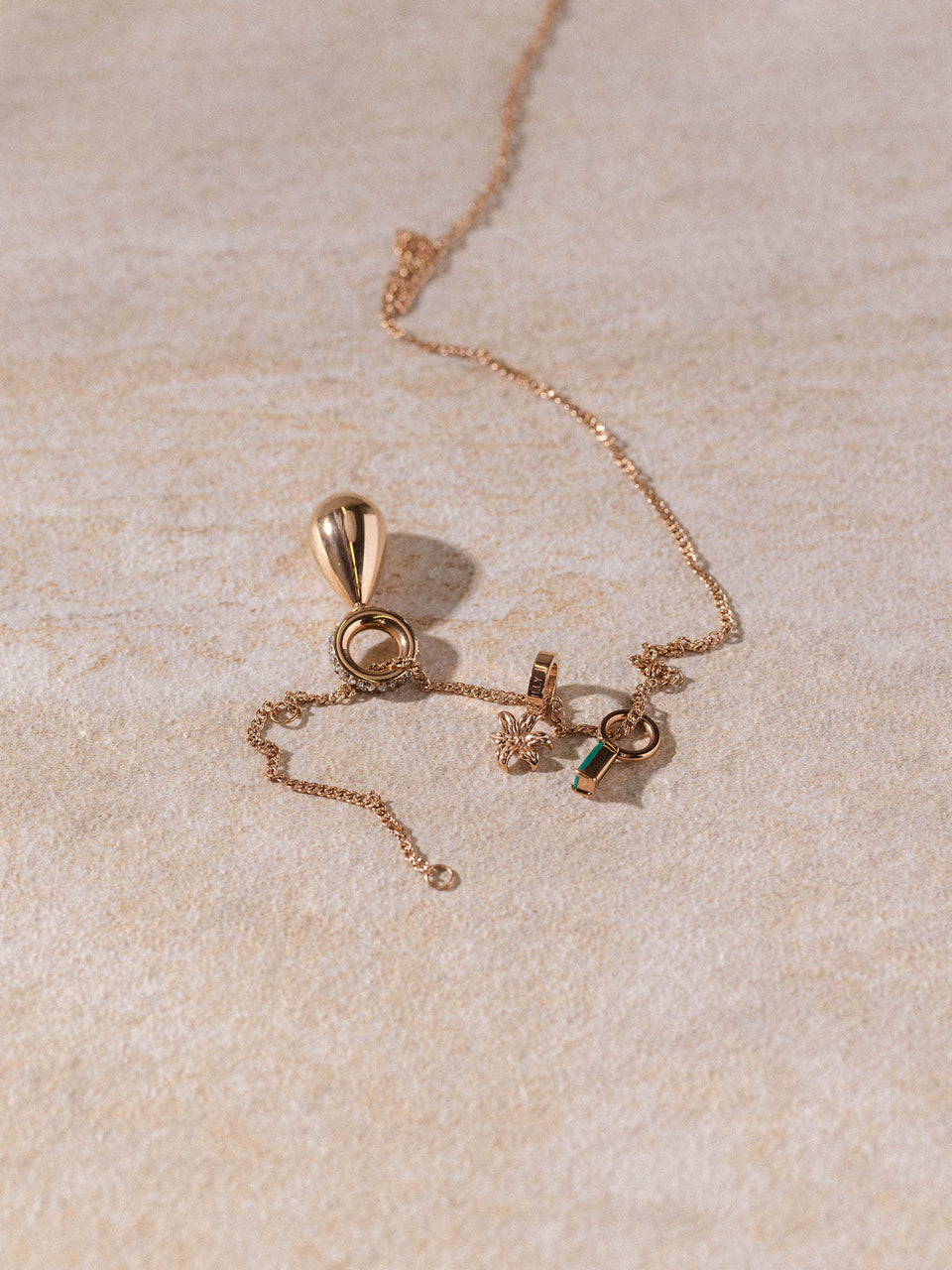 Kaula Kette in 18K Roségold mit feinem, gedrehtem Design und zarten Anhängern auf hellem Stein – PURELEI.