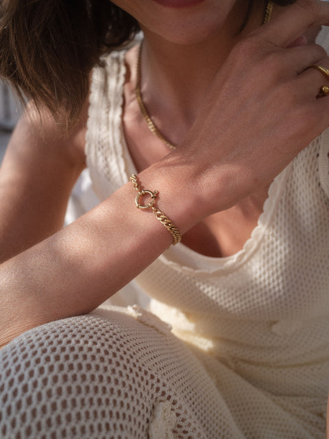 PURELEI Bold Charm Armband aus goldfarbenem Edelstahl mit Charm-Verschluss, elegant am Handgelenk getragen.