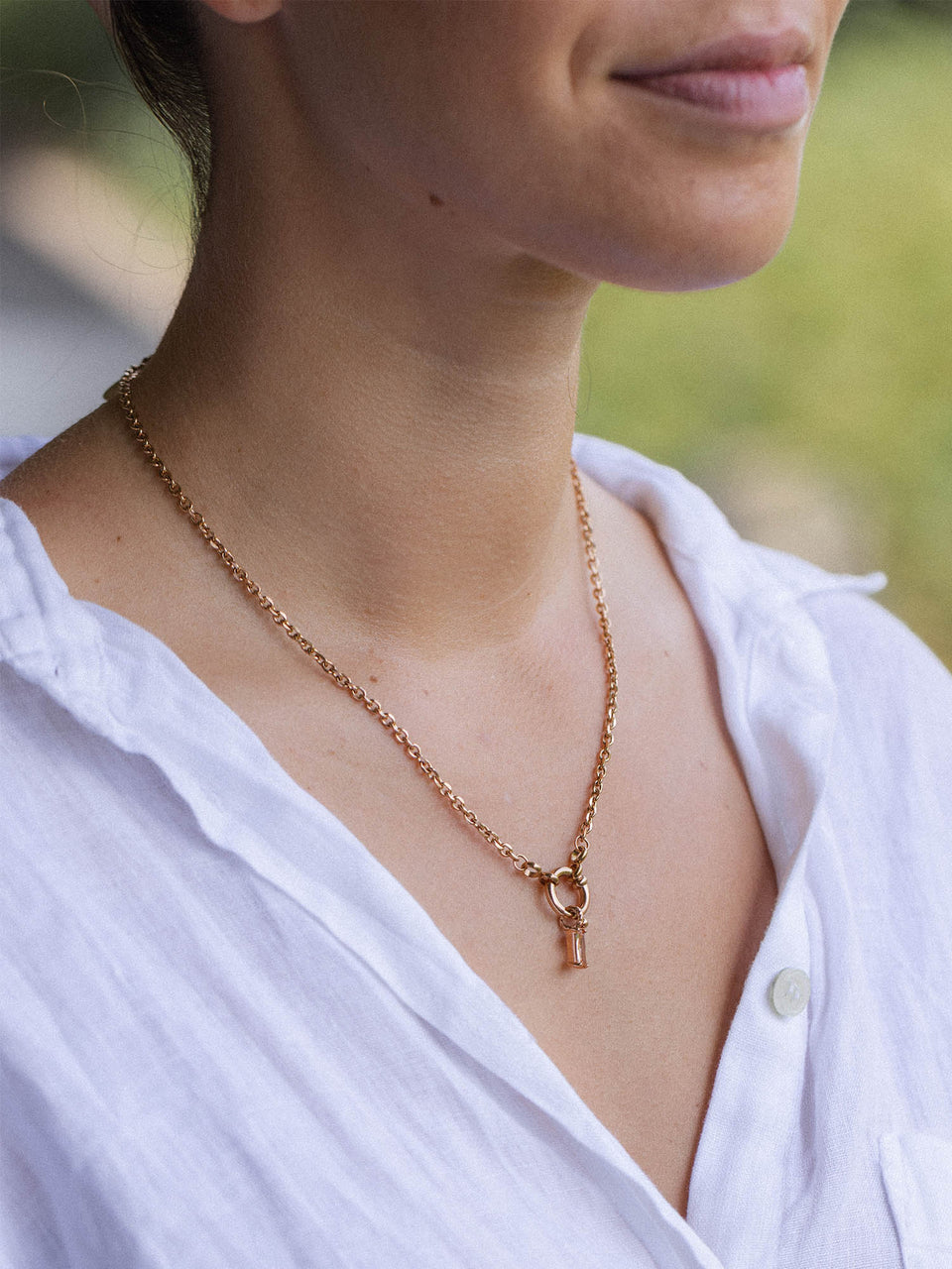 PURELEI Canyon Charm in 18K Roségold mit champagnerfarbenem Zirkonia, fein und elegant am Dekolleté getragen.