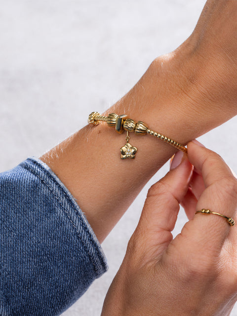 Lei Charm Armreif von PURELEI aus 14K vergoldetem Edelstahl mit Pikakeblüten-Design und zwei Stopper-Charms auf weißem Hintergrund