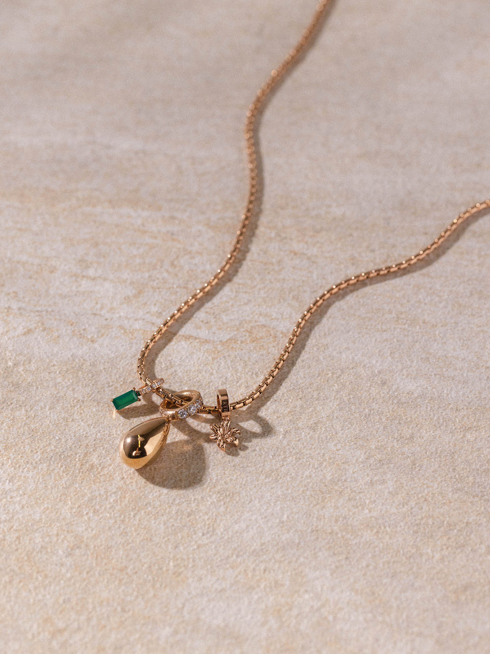 PURELEI Resonance Kette in roségold mit edlen Charms auf warmem Sand – elegant und feminin.