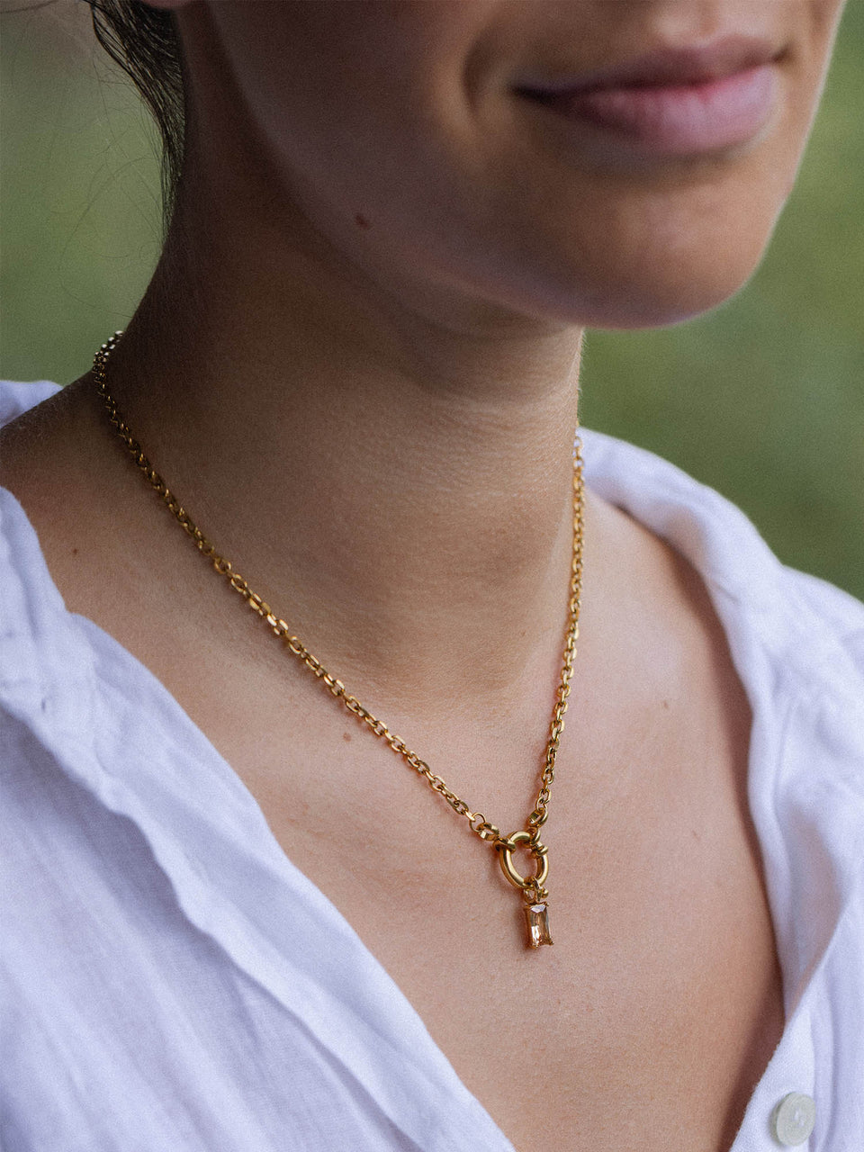 PURELEI Canyon Charm Kette in 18K Gold mit champagnerfarbigem Zirkonia, elegant und zeitlos am Hals getragen.