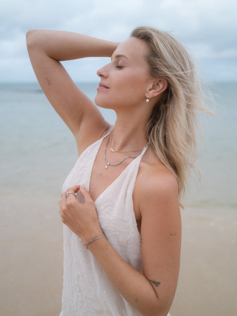 Elegante PURELEI Schmuckstücke in Silber, getragen am Strand, strahlen feminine Leichtigkeit aus.