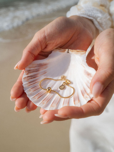 Roségoldenes Armband auf Muschel, in sanften Strandfarben gehalten – PURELEI.