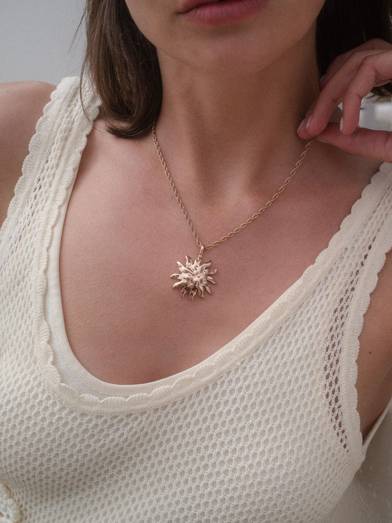 PURELEI Iconic Sun Charm aus goldfarbenem Edelstahl mit strukturiertem Sonnenanhänger, elegant und feminin getragen.