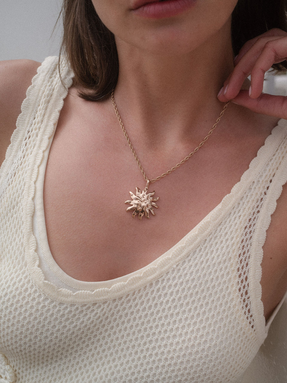 PURELEI Iconic Sun Charm aus goldfarbenem Edelstahl mit strukturiertem Sonnenanhänger, elegant und feminin getragen.