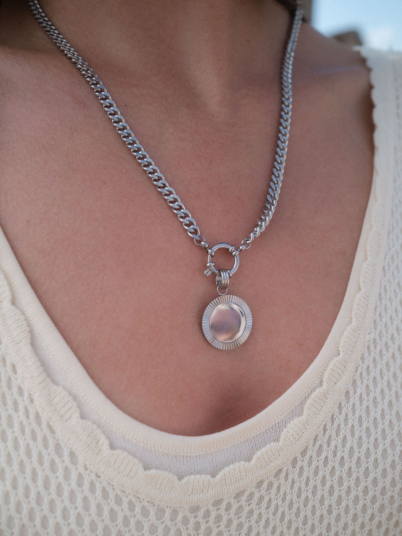 Inner Circle Charm aus nickelfreiem Silber mit geriffeltem Sonnenmotiv, getragen zu luftigem Top – PURELEI Eleganz.