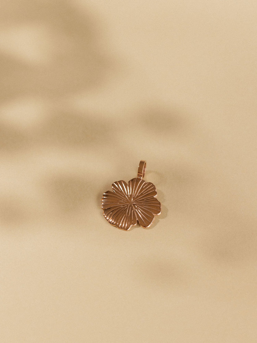 Bronzener Hibiskus-Anhänger auf sanftem Hintergrund, PURELEI inspiriert.