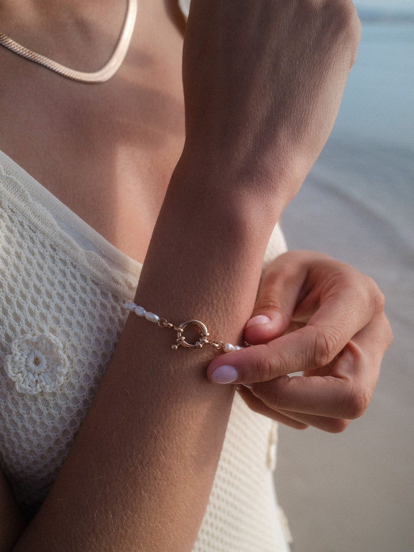 Charm Armband mit Perlen aus vergoldetem Edelstahl und Süßwasserperlen, getragen in natürlichem, warmem Licht von PURELEI