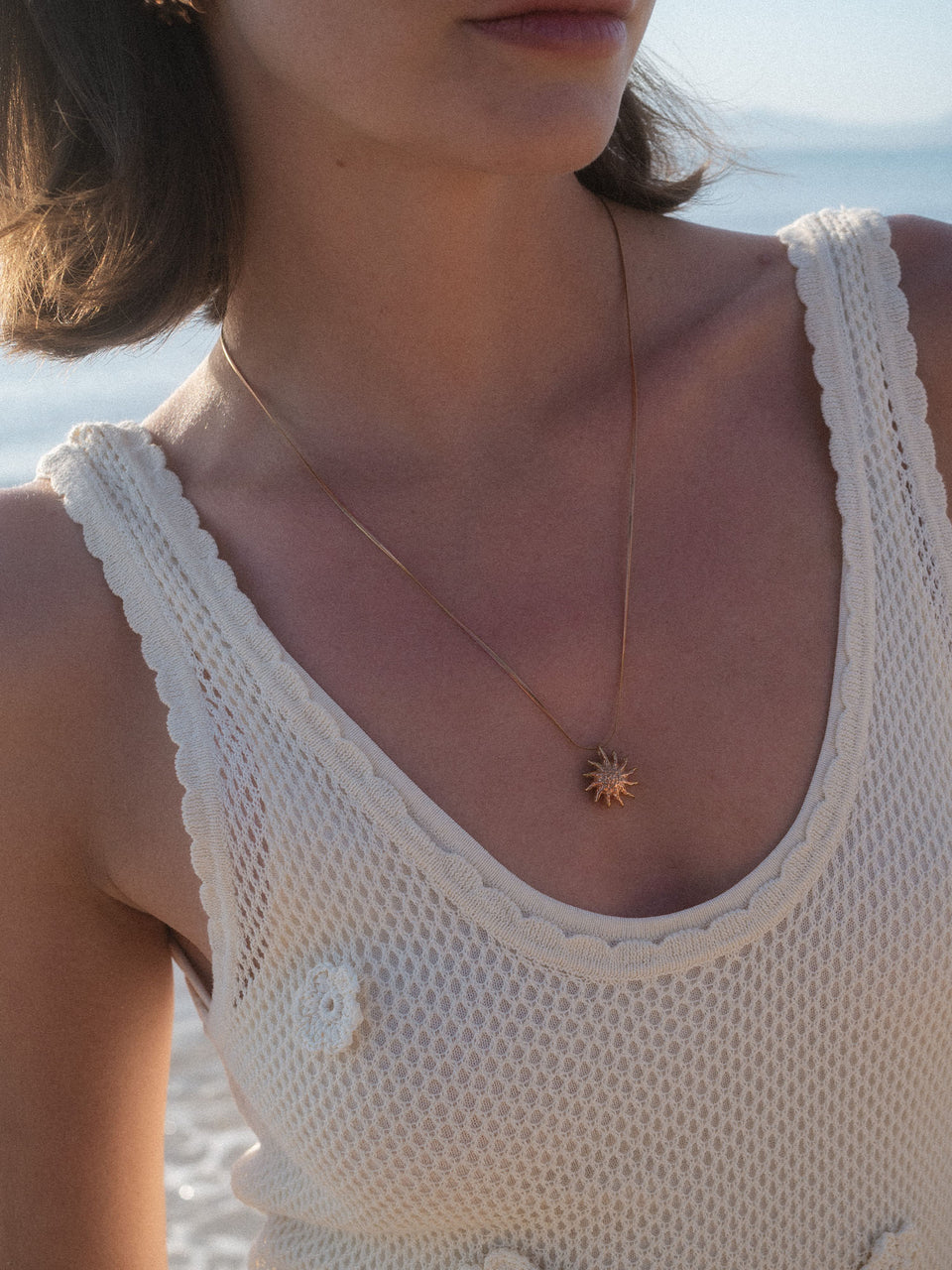 PURELEI Iconic Sun Kette in Roségold mit filigraner Snake-Chain und sonnigem Anhänger am Strand getragen.