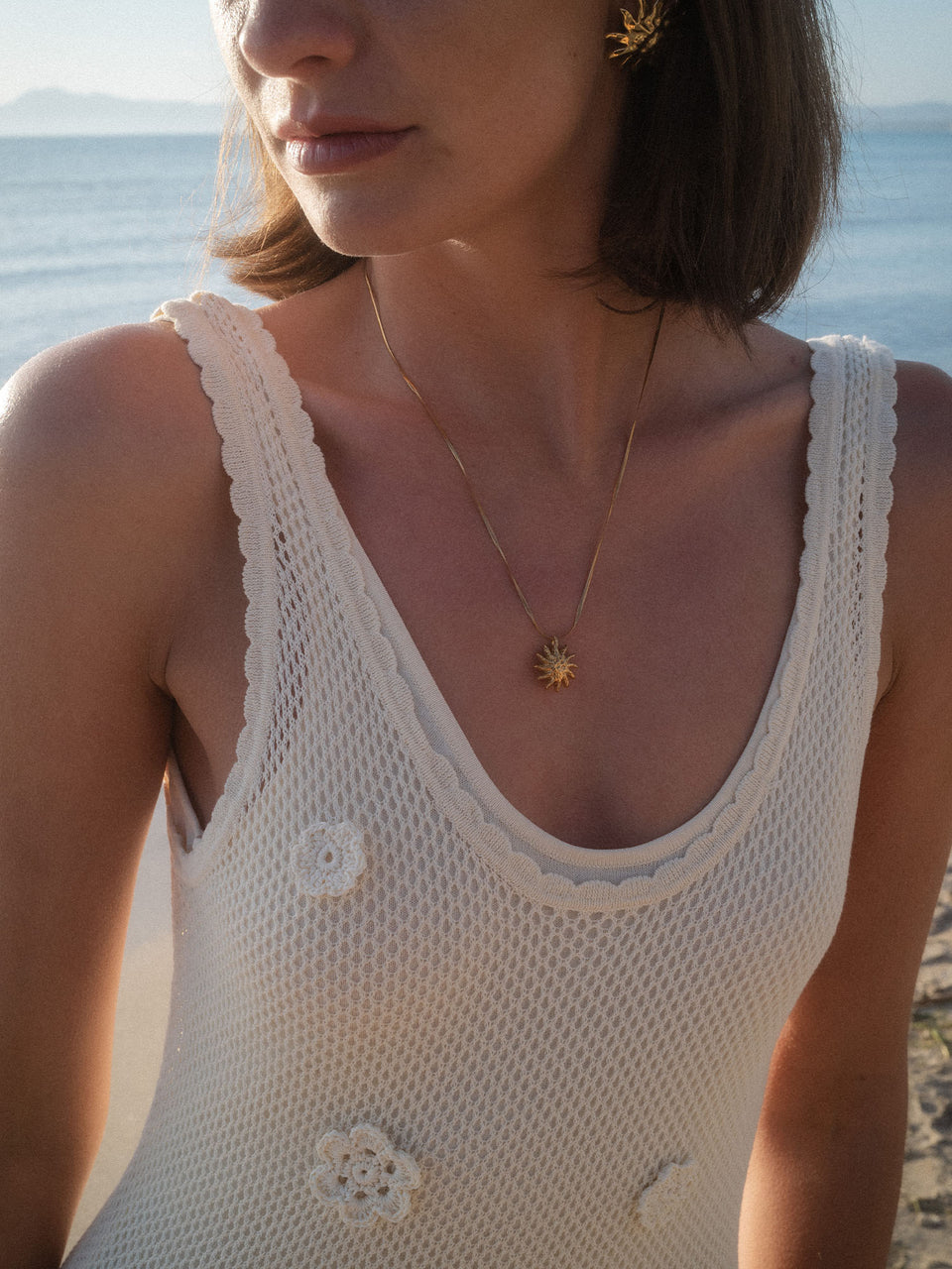 PURELEI Iconic Sun Kette in 14K Gold mit filigranem Sonnenanhänger, zart im warmen Strandlicht getragen.
