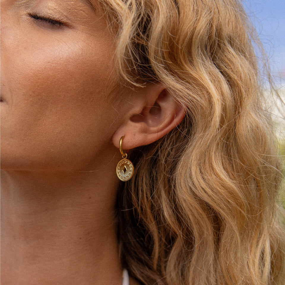 PURELEI Lolani Ohrringe goldene Creolen mit gemustertem Coin, elegant und feminine Island-Ästhetik am Ohr getragen
