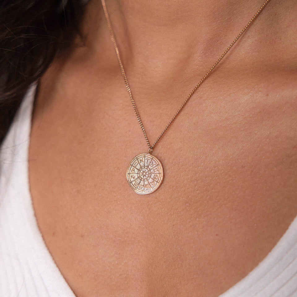 PURELEI Zodiac Kette in 18K Gold, zartes Sternzeichen-Anhänger-Design, elegant am Dekolleté getragen.