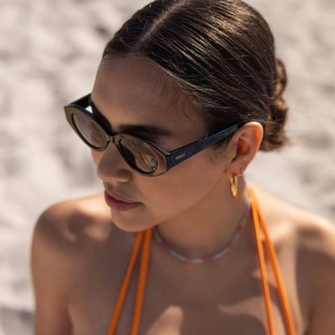 Dunkle Sonnenbrille von PURELEI, elegant und modern, getragen am Strand.
