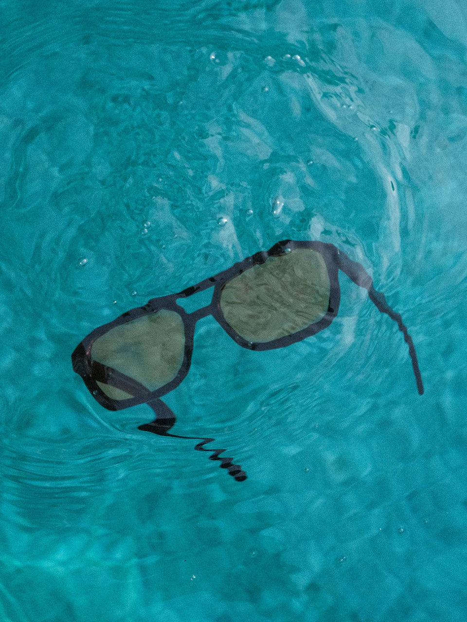 Summer Haze Sonnenbrille von PURELEI, schwarzer Acetatrahmen mit braunen Gläsern, elegant im Wasser schwebend.
