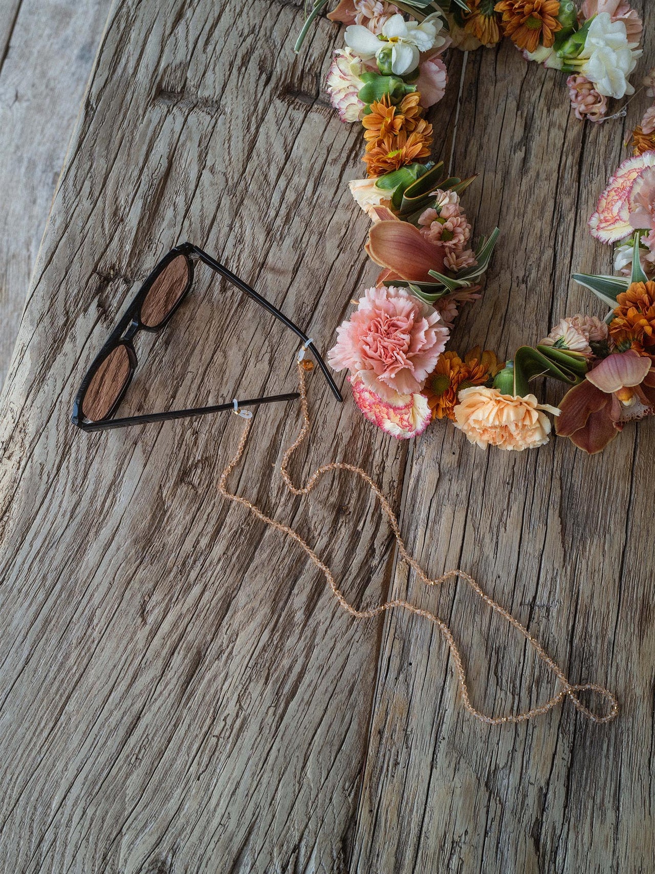 PURELEI Summer Haze Sonnenbrille in Schwarz mit braunen Gläsern und goldenem Logo, elegant auf Holzbrett inszeniert.
